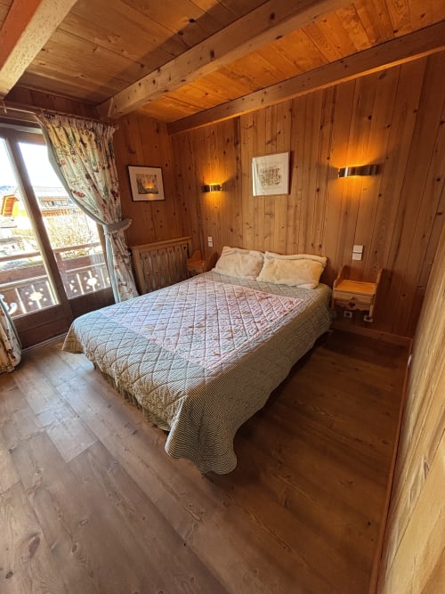 Chambre douillette en bois avec lit queen, plafond à poutres et balcon avec vue montagne à Chez Francine