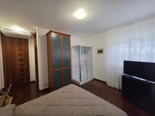 Double bedroom at Villa Andreina in Sarnano with bed, wardrobe, shower enclosure, TV and garden views