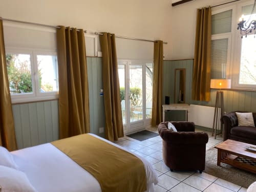 Schlafzimmer des Cottage Le Gueuloir mit Meerblick, goldenen Vorhängen, braunem Sessel und Zugang zur Terrasse in Destination Etretat