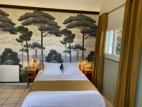 Schlafzimmer des Cottage Le Gueuloir mit weißer Bettwäsche, goldenen Akzenten, Waldmotiv-Kopfteil, Holznachttischen, Meerblick auf Étretat