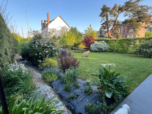 Jardin verdoyant de Destination Etretat avec pelouse impeccable, arbustes fleuris et charmants bâtiments historiques