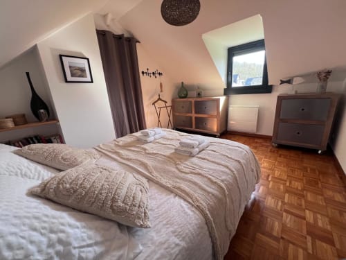 Chambre mansardée cosy à Destination Etretat avec lit double, mobilier en bois et lucarne sur Etretat