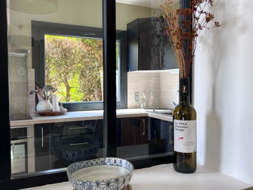 Cuisine moderne à Destination Etretat avec bouteille de vin, bol décoratif et vue sur la verdure d'Etretat