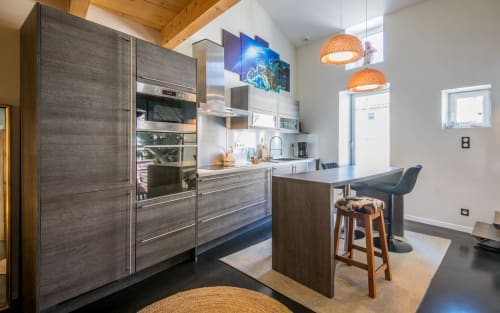 Cuisine moderne de l'appartement duplex Le Sérénité à Millau, avec armoires en bois foncé, appareils inox et îlot