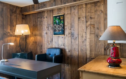 Espace de travail dans un petit immeuble au cœur de Millau, avec lambris en bois, lampes de bureau, fauteuil bleu et tableaux de montagne.