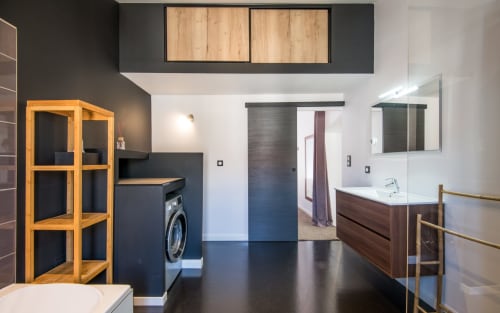 Salle de bain épurée d'un duplex moderne à Millau avec meuble en bois, vasque sombre, douche vitrée et lave-linge