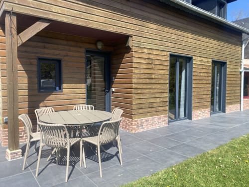 Terrasse extérieure avec table et chaises de repas à l'hôtel Destination Etretat à Etretat, France, avec bardage bois et ton sombre