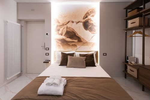 Camera moderna alle Michelangelo Central Suites di Firenze con letto king, biancheria marrone e murale artistico