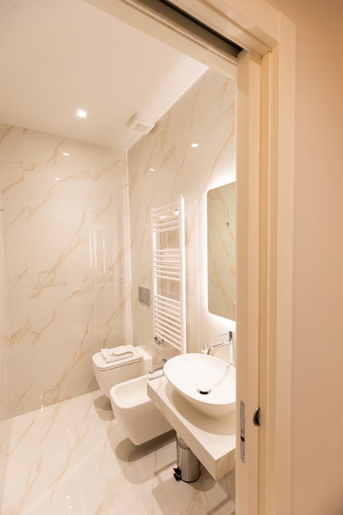 Bagno di lusso moderno nelle Michelangelo Central Suites Firenze con pareti in marmo, lavabo, wc e scaldasalviette