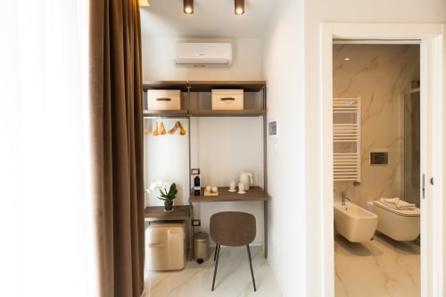 Area scrivania nella camera deluxe di Michelangelo Central Suites a Firenze con toletta, sedia e ingresso al bagno