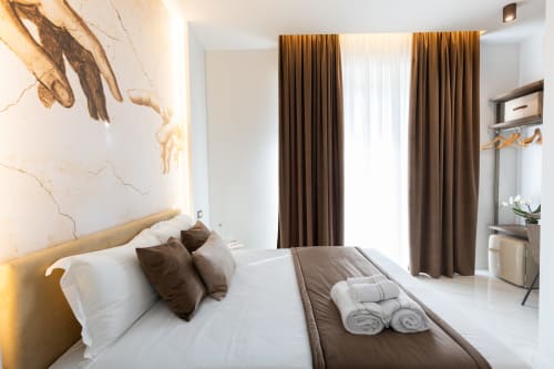 Camera da letto lussuosa con arredamento moderno, tende marroni e dettagli in marmo presso le Michelangelo Central Suites di Firenze