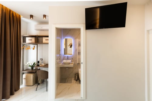 Camera Deluxe presso Michelangelo Central Suites Firenze con TV, area lavoro e moderno bagno privato con specchio illuminato