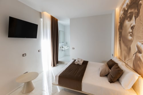 Camera moderna alle Michelangelo Central Suites di Firenze con letto matrimoniale, dettagli marrone, TV a schermo piatto e elementi scultorei