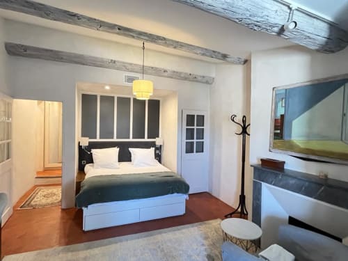 Modern bedroom suite at Les Suites de Montigny in Aix-en-Provence with queen bed, exposed wooden beams, and garden view