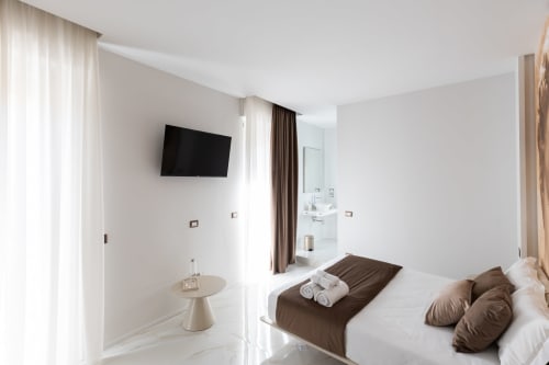 Moderna camera doppia superior presso Michelangelo Central Suites a Firenze con TV a parete, dettagli marrone e bagno privato
