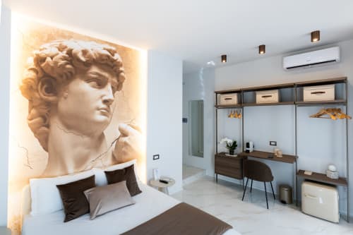 Camera moderna presso Michelangelo Central Suites a Firenze con scultura classica, letto e zona di lavoro con ripostiglio.