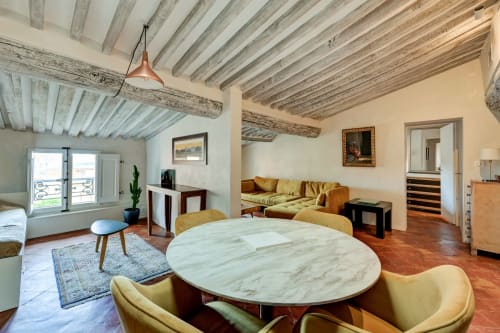 Suite Cézanne at Les Suites de Montigny in Aix-en-Provence features exposed wooden beams, marble dining table, yellow chairs,