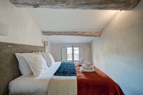 Bright bedroom in Suite Cézanne at Les Suites de Montigny, Aix-en-Provence, featuring exposed wooden beams, white bedding,