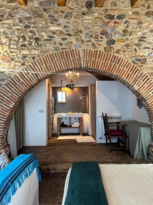 Habitación doble con arco de ladrillo rústico en Hotel Can Carbó de les Olives de Perelada, con camas y acceso a baño privado