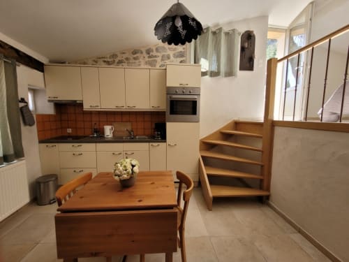 Cuisine-séjour contemporain au Gîte des Anges avec table en bois, kitchenette équipée aux carreaux orange et