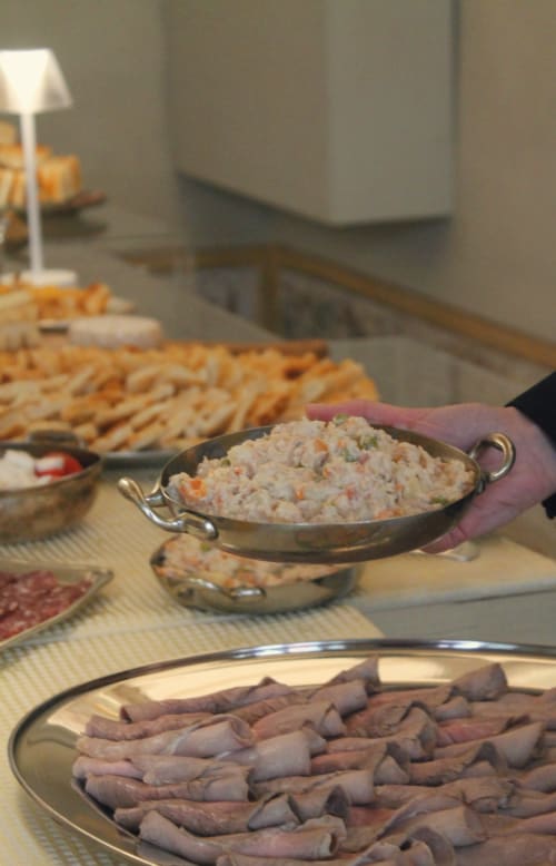 Ospite che tiene un piatto di antipasti al buffet di Palazzo Fauzone Relais & Spa con salumi e cracker