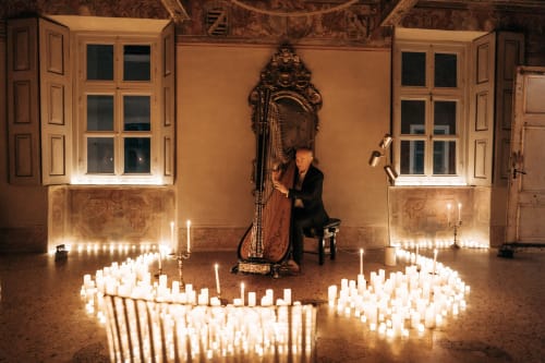 Elegante arpista in concerto nella sala barocca illuminata da candele del Palazzo Fauzone Relais & Spa, Mondovì