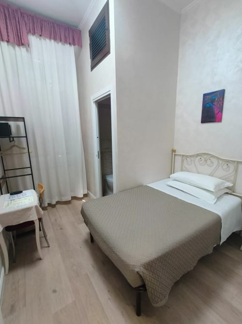 Camera singola economy dell'Hotel Principe Amedeo a Roma con letto, tende bianche, scrivania e accesso al bagno