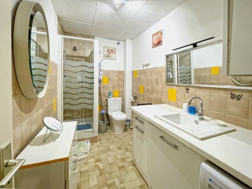 Salle de bain moderne au studio Le Vallon des Sources à Digne-les-Bains avec douche, lavabo, toilettes et carrelage jaune
