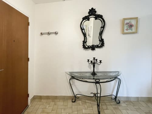 Élégante entrée de l'appartement Studio MISTRAL à Digne-les-Bains, avec miroir noir décoratif, lavabo en verre et ornements raffinés