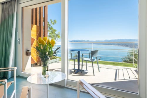 Balcone della Junior Suite con tulipani gialli, vista mare su Castellammare del Golfo, acque del golfo e montagne sotto cielo blu sereno.