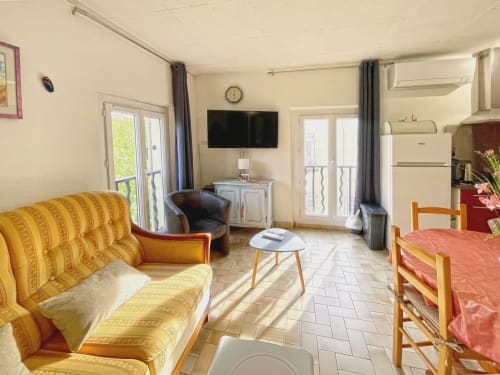 Appartement Studio MISTRAL au Vallon des Sources à Digne-les-Bains avec canapé jaune, TV, kitchenette et séjour meublé