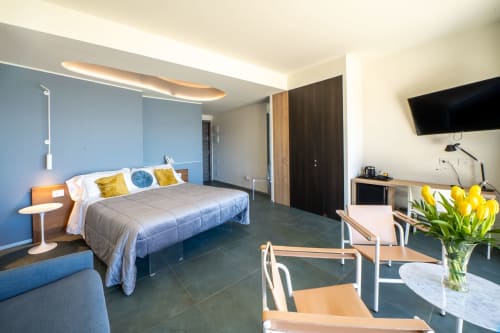 Suite Junior moderna presso Hotel Belvedere Resort con vista mare, con letto, TV, scrivania e fiori gialli a Castellammare del
