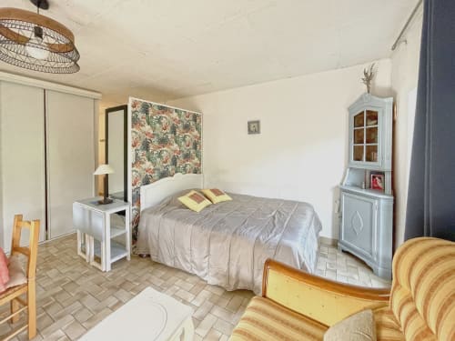 Chambre de studio à Digne-les-Bains avec lit, bureau, armoire bleu pâle et fauteuil rayé
