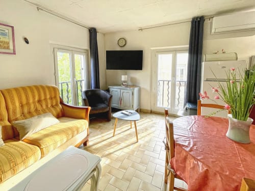 Appartement Studio MISTRAL à Digne-les-Bains avec canapé jaune, TV, coin repas et accès au balcon