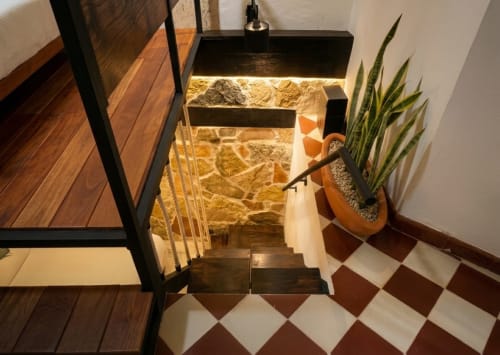 Staircase entry at Villa Merida Boutique Hotel with stone accent wall, metal railing, and potted plant decor.