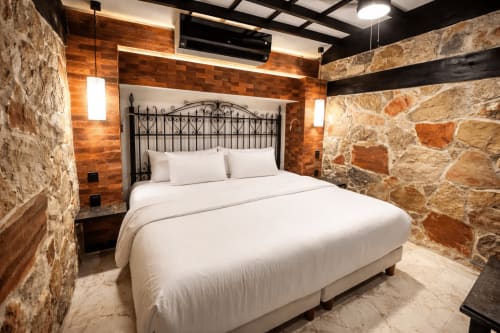 Dormitorio rústico moderno en Villa Merida Boutique Hotel con muros de piedra, acentos de madera y cama de hierro forjado en Mérida