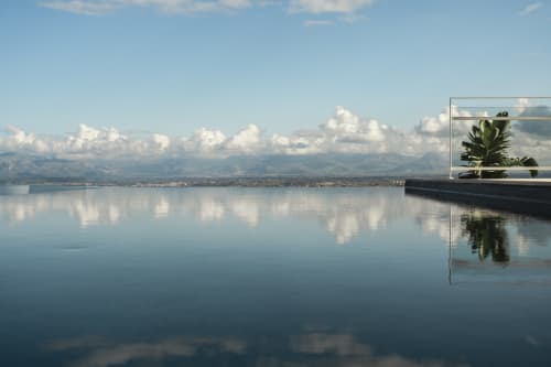 Piscina a sfioro con vista sulla baia di Castellammare del Golfo, le montagne e una pianta in vaso all'Hotel Belvedere Resort