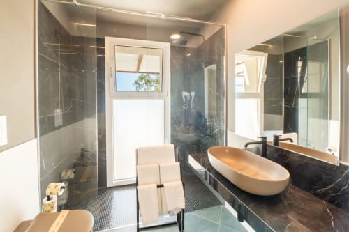 Bagno moderno dell'Hotel Belvedere Resort con pareti in marmo nero, vasca in rame indipendente, doppi lavabi e doccia walk-in