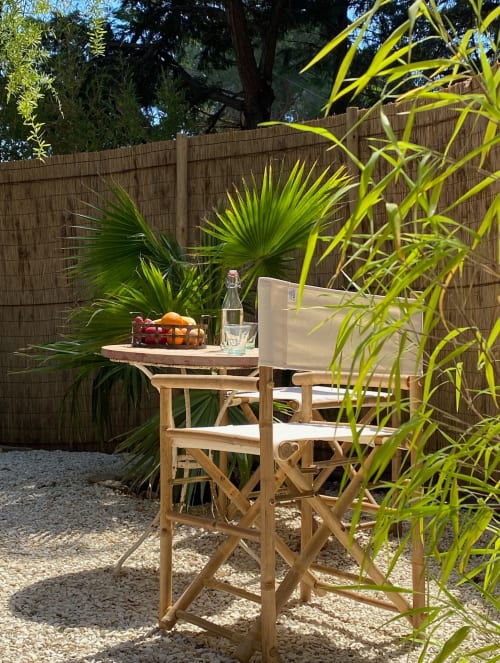 Terrasse tranquille du Patio aux Oiseaux à La Ciotat avec fauteuil metteur en scène, rafraîchissements et végétation tropicale luxuriante