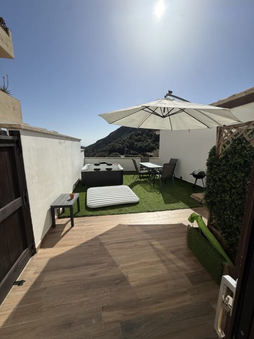 Terrazza panoramica a Sardinia Holidays con vasca idromassaggio, lettini, ombrellone, vista montagna e pavimentazione in legno