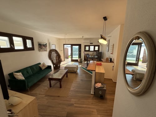 Appartamento vacanze in Sardegna a Torpè con divano verde, pavimenti in legno, porte con vista sul mare e specchio decorativo