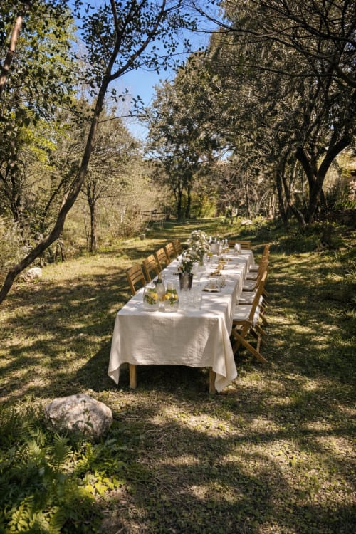 Outdoor dining table set under trees at Molí Roquer B&B in Rabós, Spain