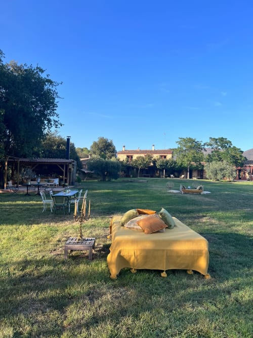 Yellow bed in green lawn at Molí Roquer rural property in Rabós, Spain with terrace and buildings