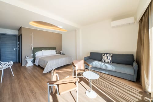 Suite moderna dell'Hotel Belvedere Resort a Castellammare del Golfo con vista sul mare, letto, divano e pavimenti in legno