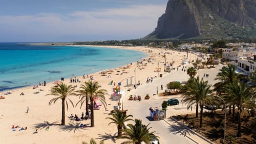 Spiaggia di Castellammare del Golfo con acque turchesi, sabbia fine, palme e spettacolare scogliera
