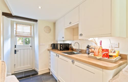 Modern cream kitchen at Cosy Llangattock Hideaway cottage in Crickhowell with wooden counters, appliances and door to garden