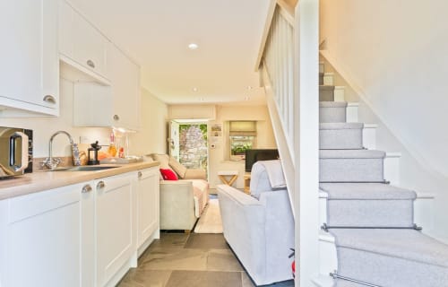 Open-plan kitchen and living area at Cosy Llangattock Hideaway cottage in Crickhowell with stairs, white cabinetry, and