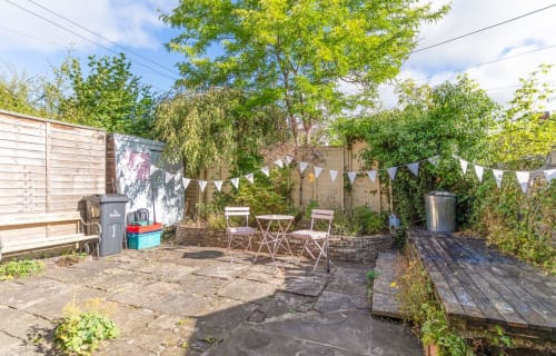 Outdoor patio area at Cosy Llangattock Hideaway cottage in Crickhowell with seating, bunting, and lush greenery