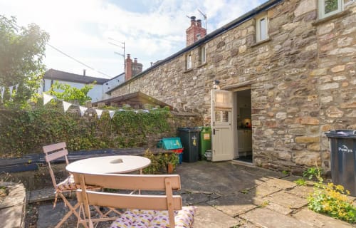 Stone cottage patio with round white table, chairs, and outdoor dining area in Crickhowell, Wales