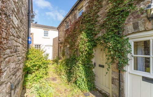 Ivy-covered stone cottage with yellow door and windows, Cosy Llangattock Hideaway in Crickhowell, Wales.
